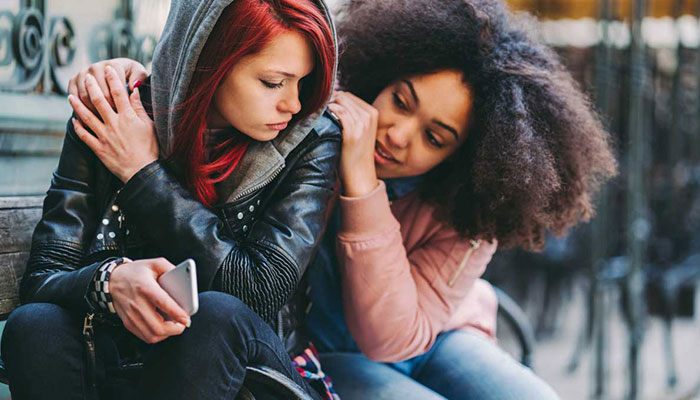 Two teen girls lean on each other